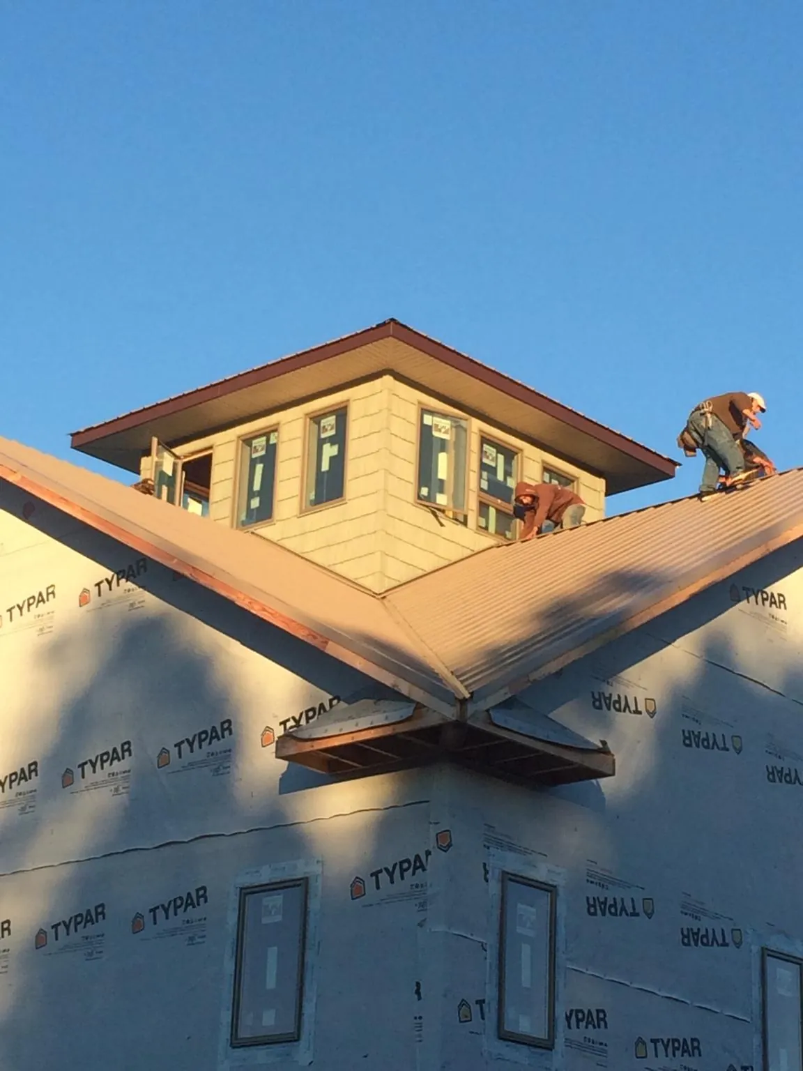 Roofers working around a rooftop cupola on a new metal roof at sunset — Roof Waterproofing in Racine by Roofing Brothers